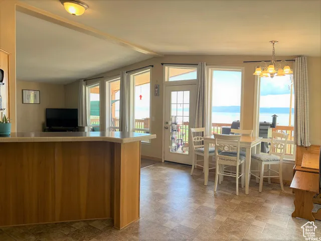 Kitchen with a water view, hanging light fixtures, a chandelier, light countertops, and stone finish flooring