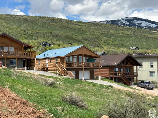 Back of house featuring a deck with mountain view, stairway, a garage, and driveway
