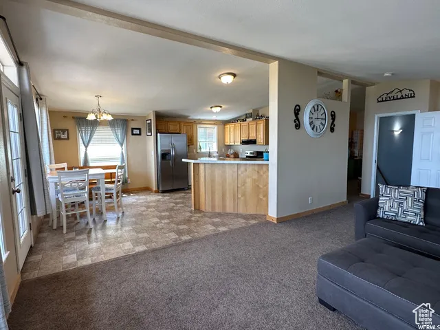 Living room featuring light carpet, vaulted ceiling, and a chandelier