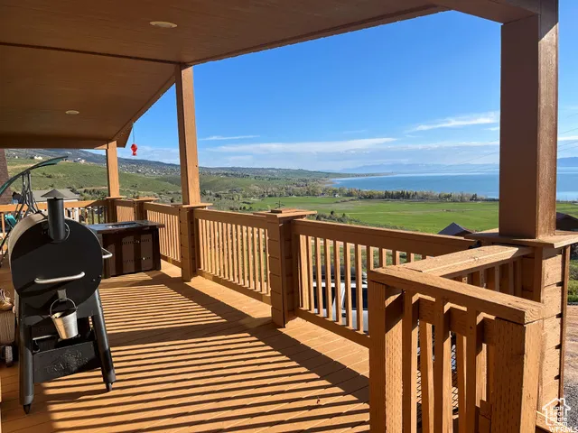 Wooden terrace featuring area for grilling and a water view