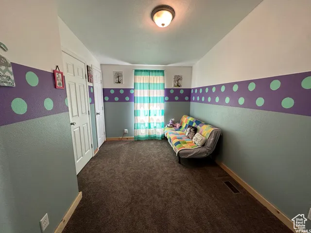 Unfurnished bedroom with dark carpet and a textured wall