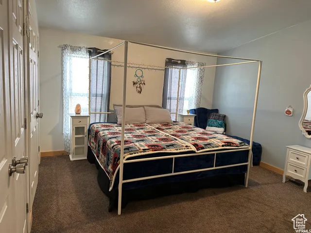 Bedroom featuring dark colored carpet, a closet, and a textured ceiling