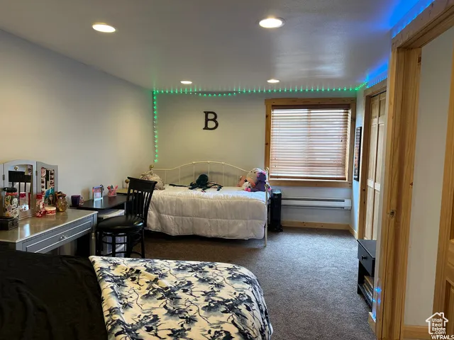 Bedroom with dark colored carpet, recessed lighting, and a baseboard heating unit