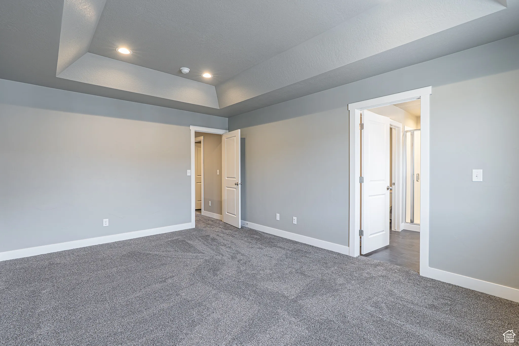 Empty room featuring dark colored carpet, a tray ceiling, and recessed lighting