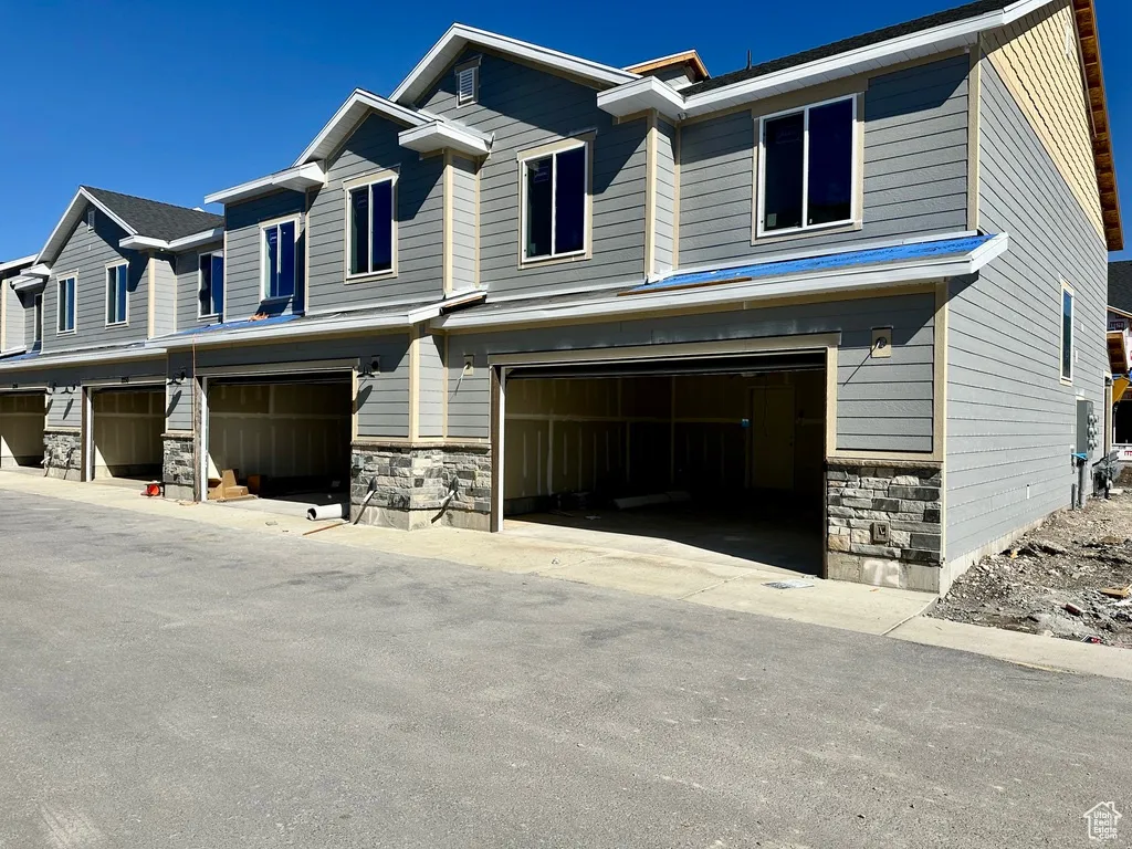 Craftsman-style home featuring stone siding, a garage, and driveway