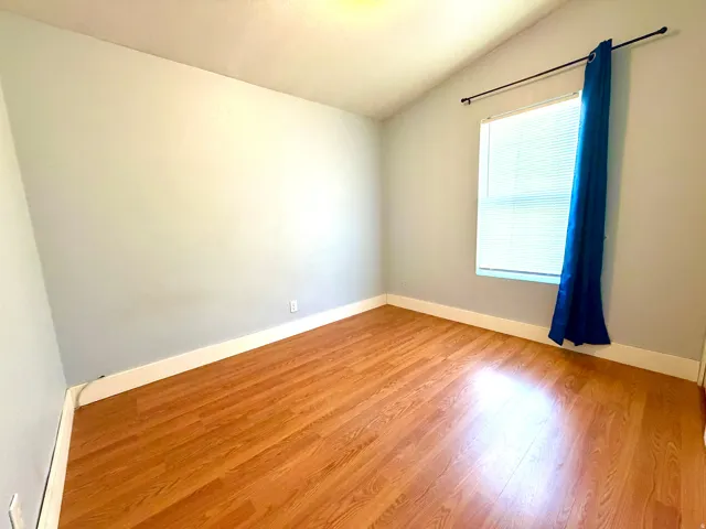 Spare room featuring lofted ceiling and light wood-style floors