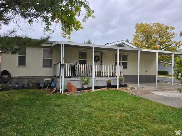 Manufactured / mobile home featuring a front yard, a porch, and a carport