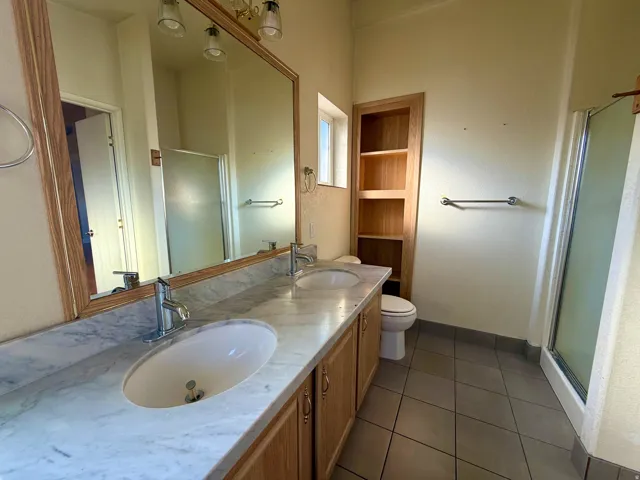 Bathroom with a stall shower, double vanity, and dark tile patterned flooring