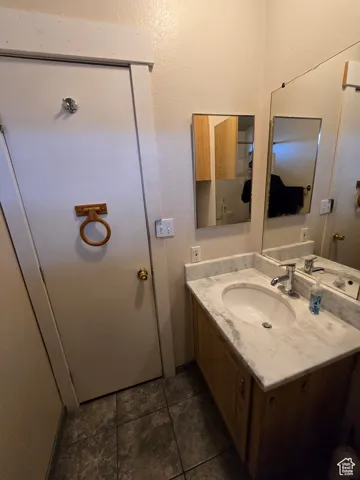 Bathroom with vanity, dark tile patterned flooring, and a textured wall