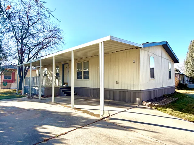 Manufactured / mobile home featuring concrete driveway, a carport, and covered porch