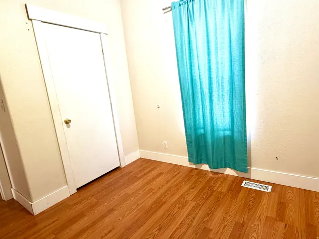 Unfurnished bedroom featuring wood finished floors and baseboards