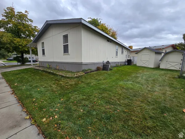 View of side of property with a storage unit and a lawn