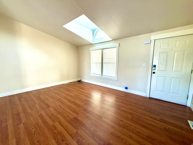 Foyer entrance with a skylight and wood finished floors