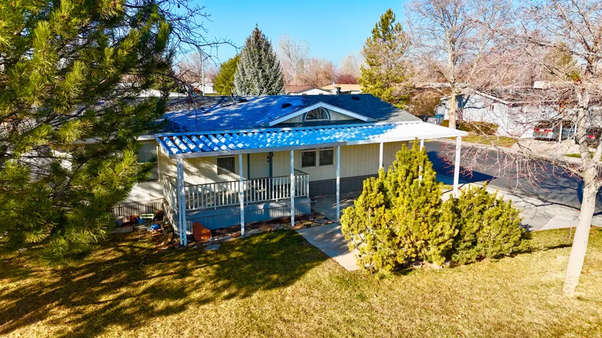View of front of house with covered porch, a front yard, and a shingled roof