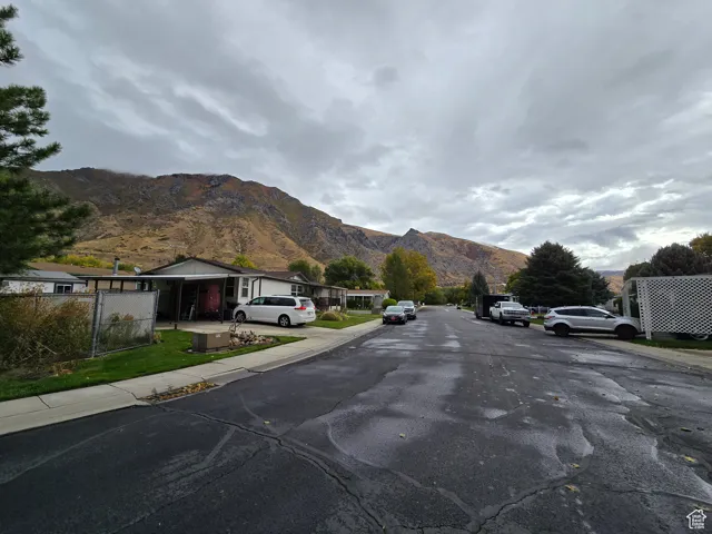 View of asphalt road with a mountain view, sidewalks, and curbs