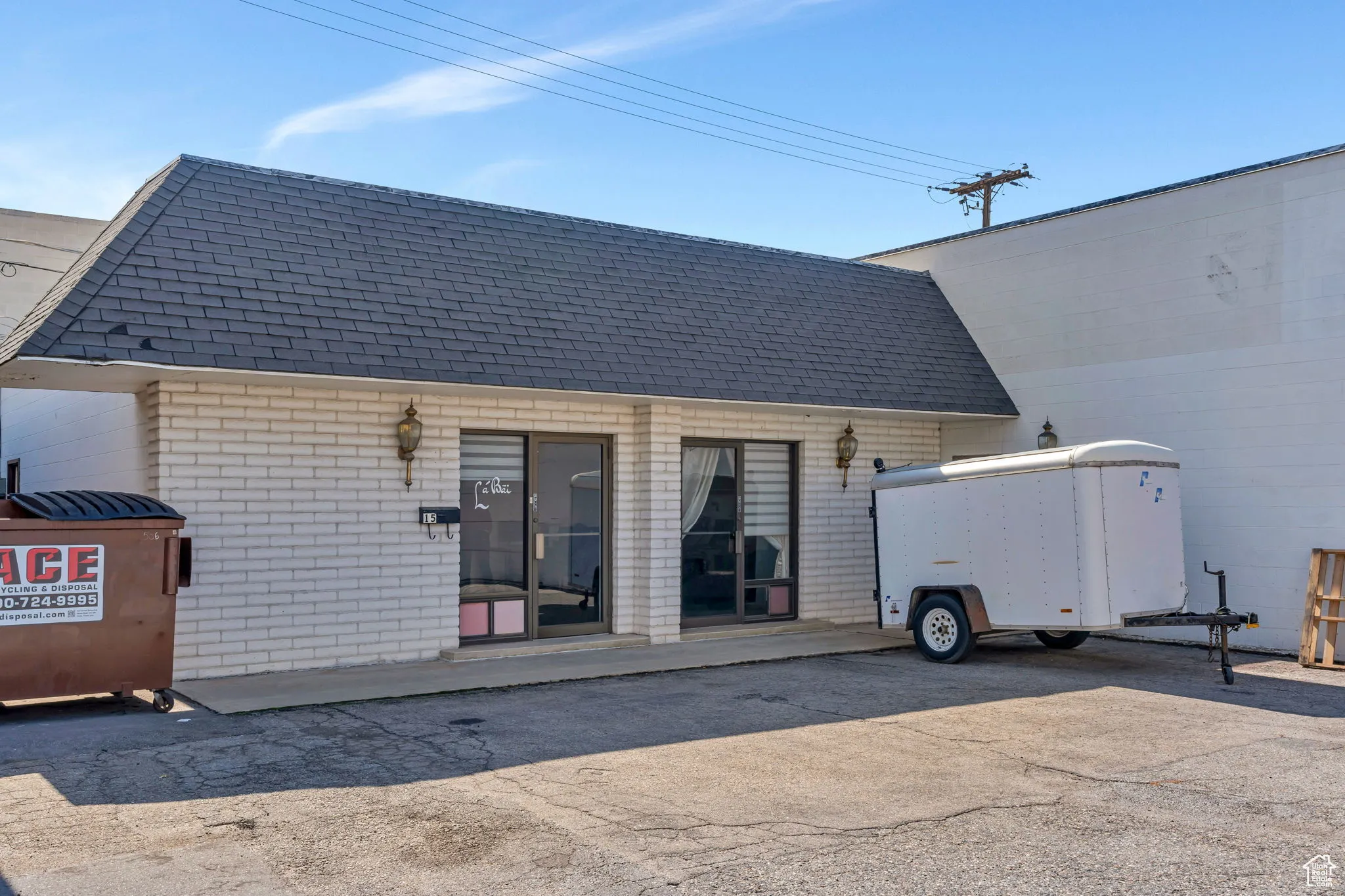 Back of house featuring a shingled roof and brick siding