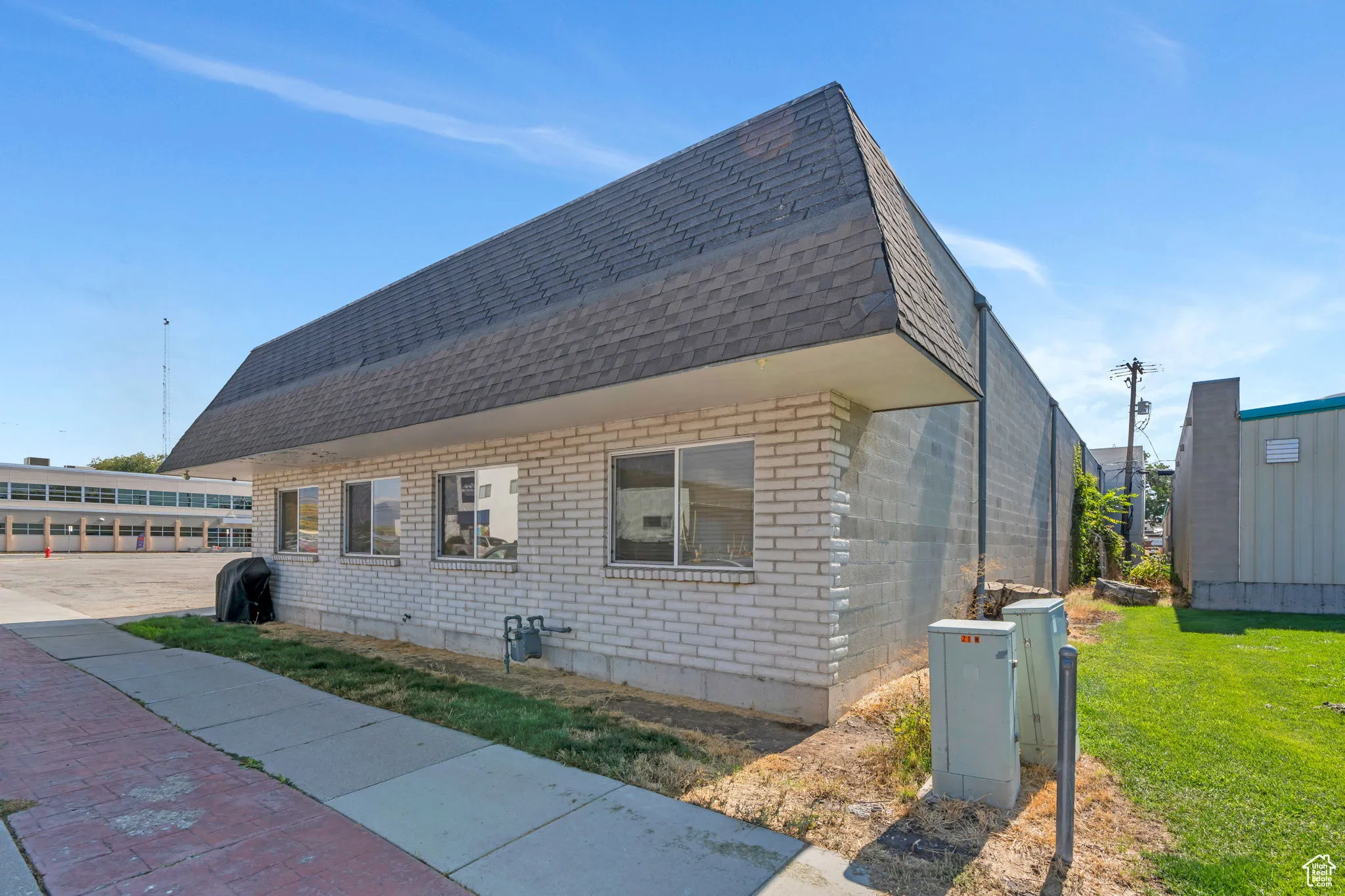 View of side of property with a shingled roof, brick siding, and a lawn