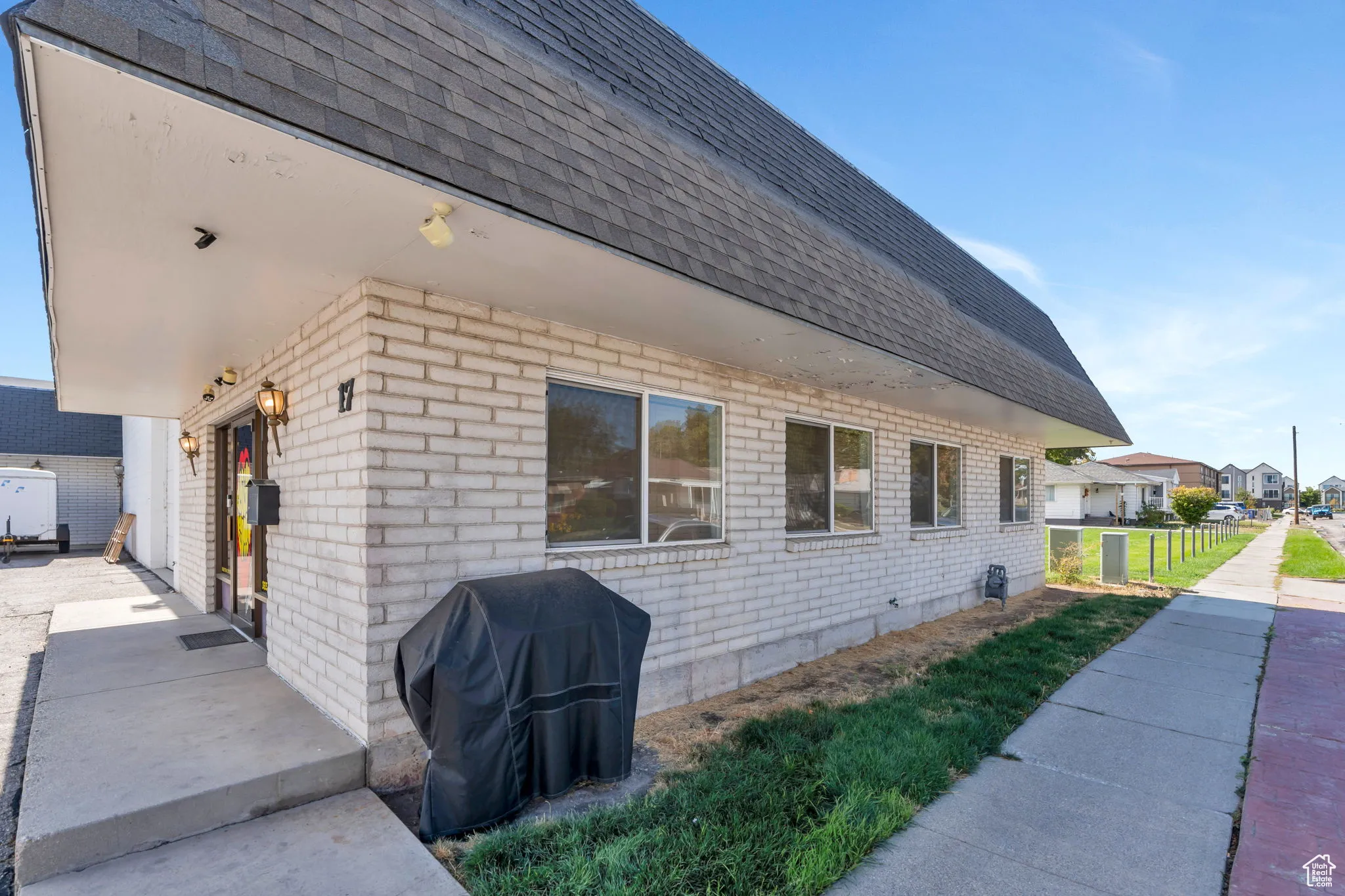View of home's exterior featuring roof with shingles, brick siding, and a lawn