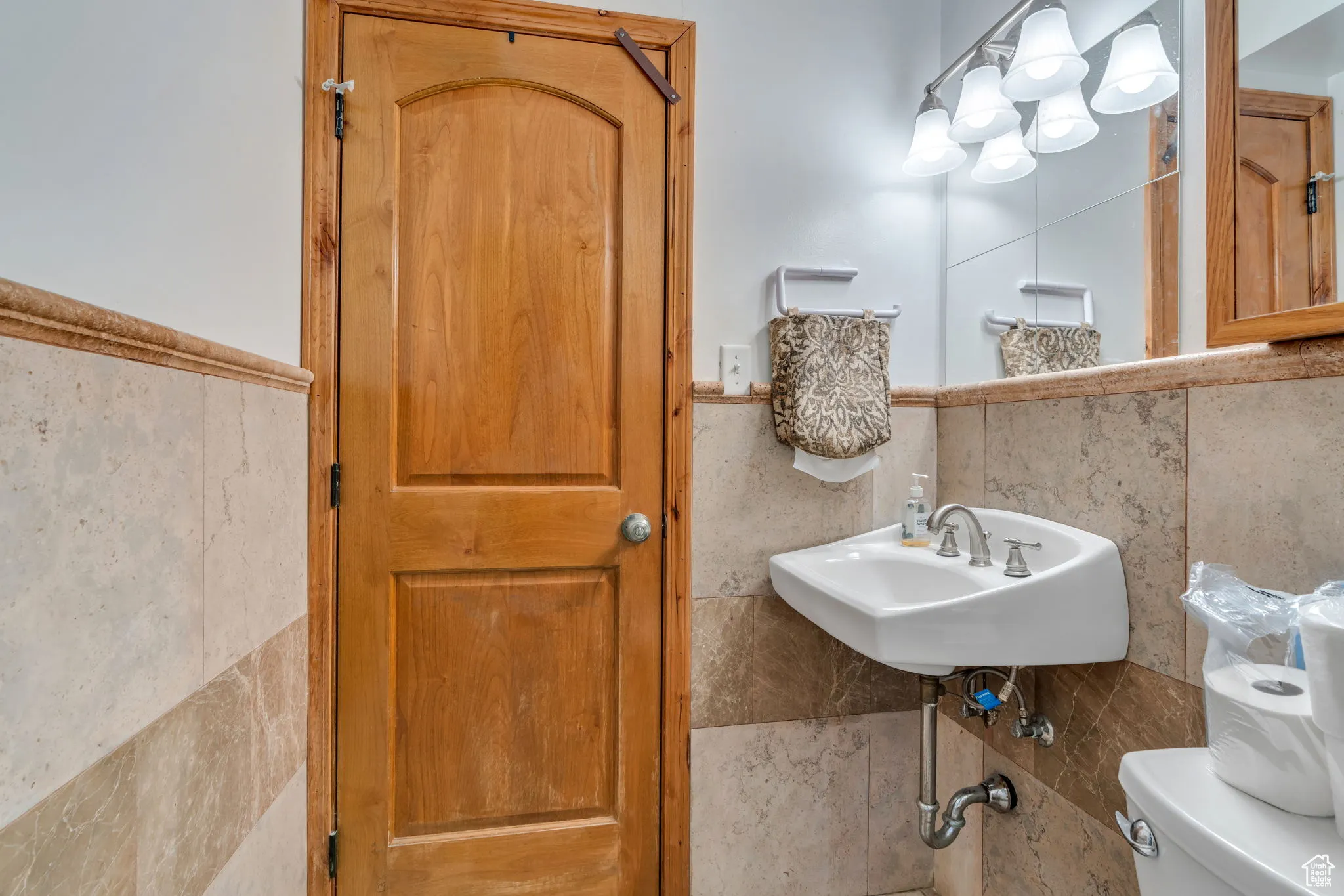 Half bath featuring tile walls and wainscoting