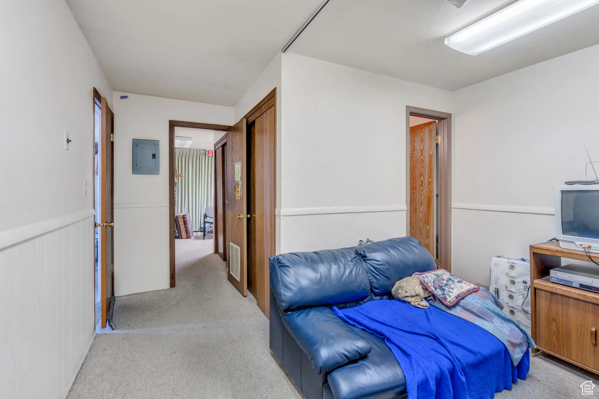 Carpeted bedroom with electric panel and wainscoting