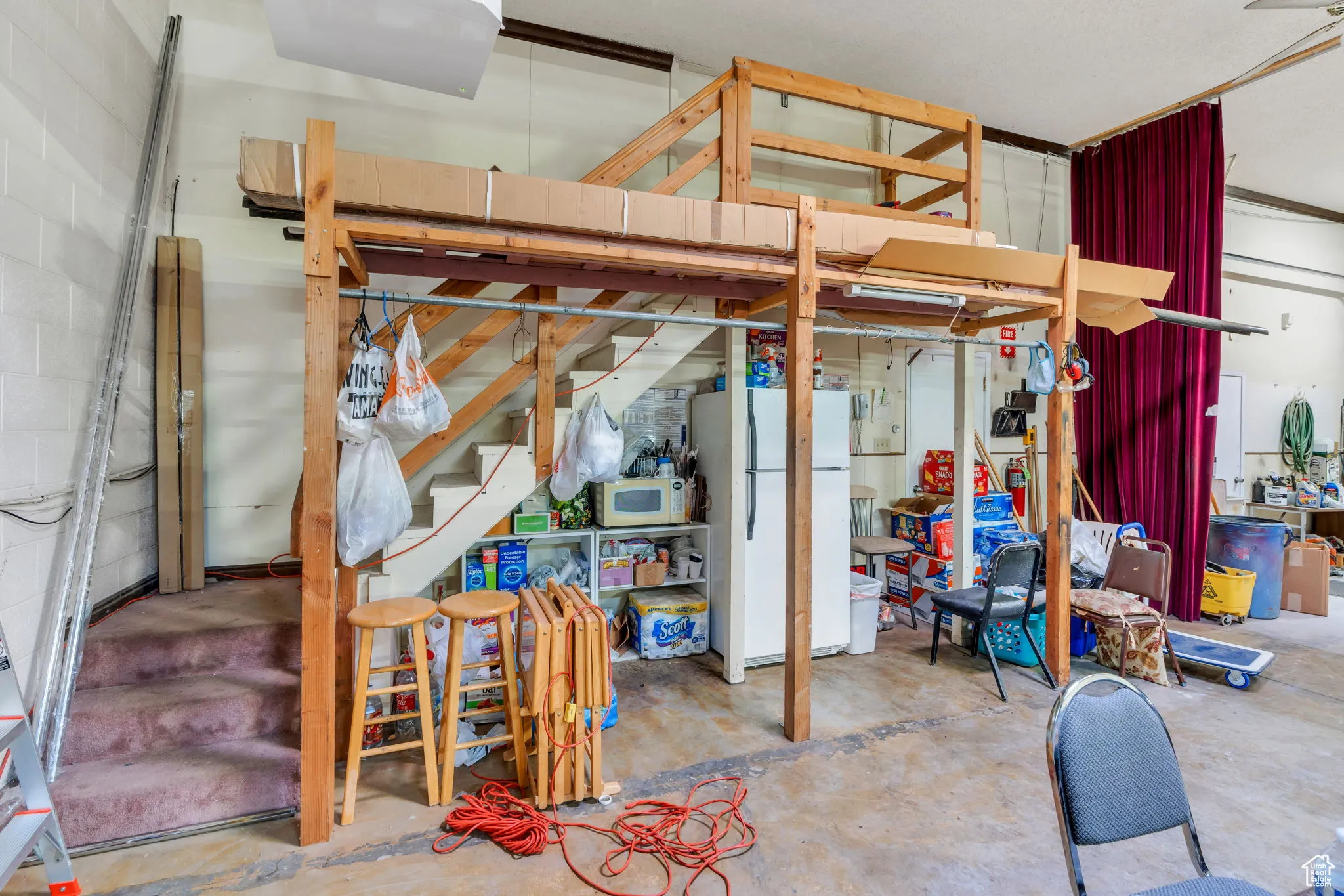 Basement featuring freestanding refrigerator and stairs