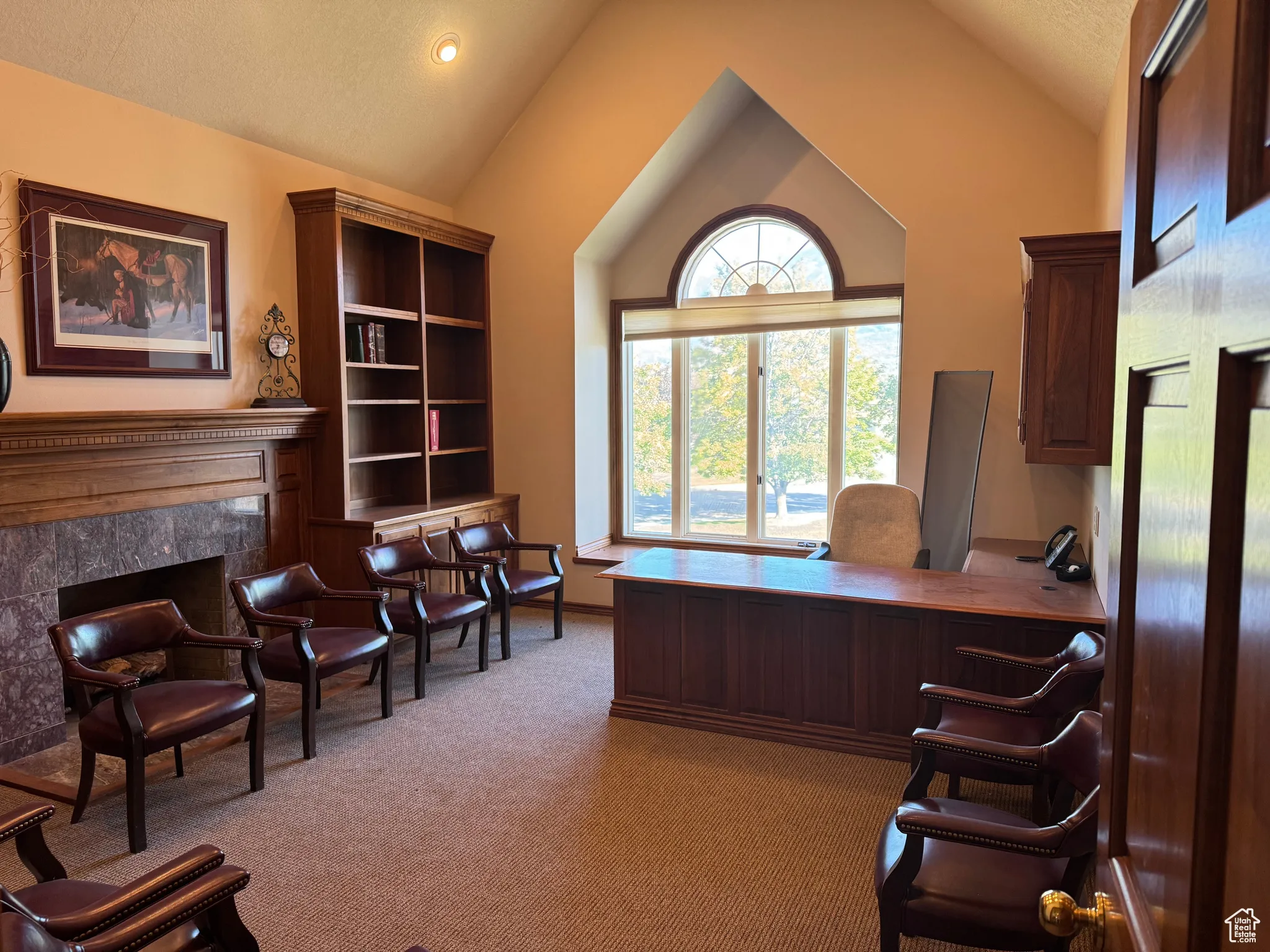 Office area featuring light colored carpet, a high end fireplace, and high vaulted ceiling