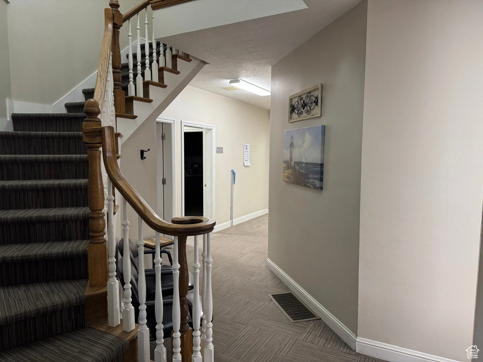 Stairway with carpet floors and a textured ceiling