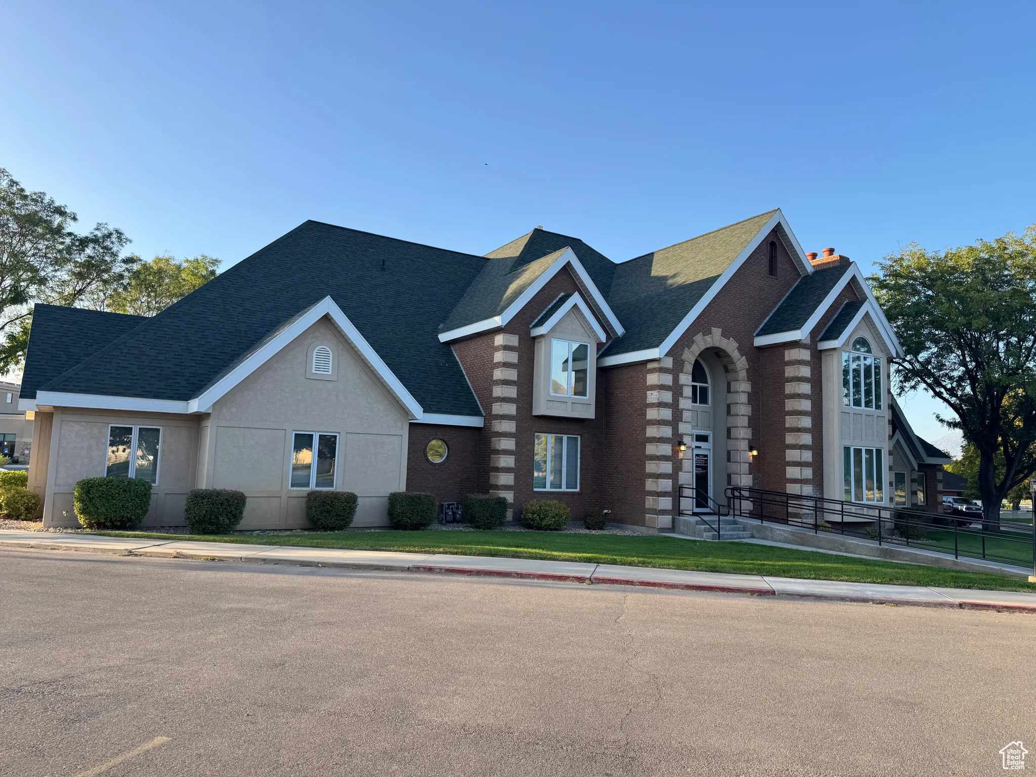 View of front facade featuring a shingled roof, a chimney, and brick siding