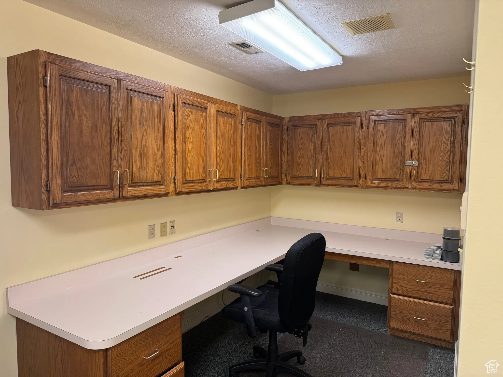 Home office featuring built in study area and a textured ceiling