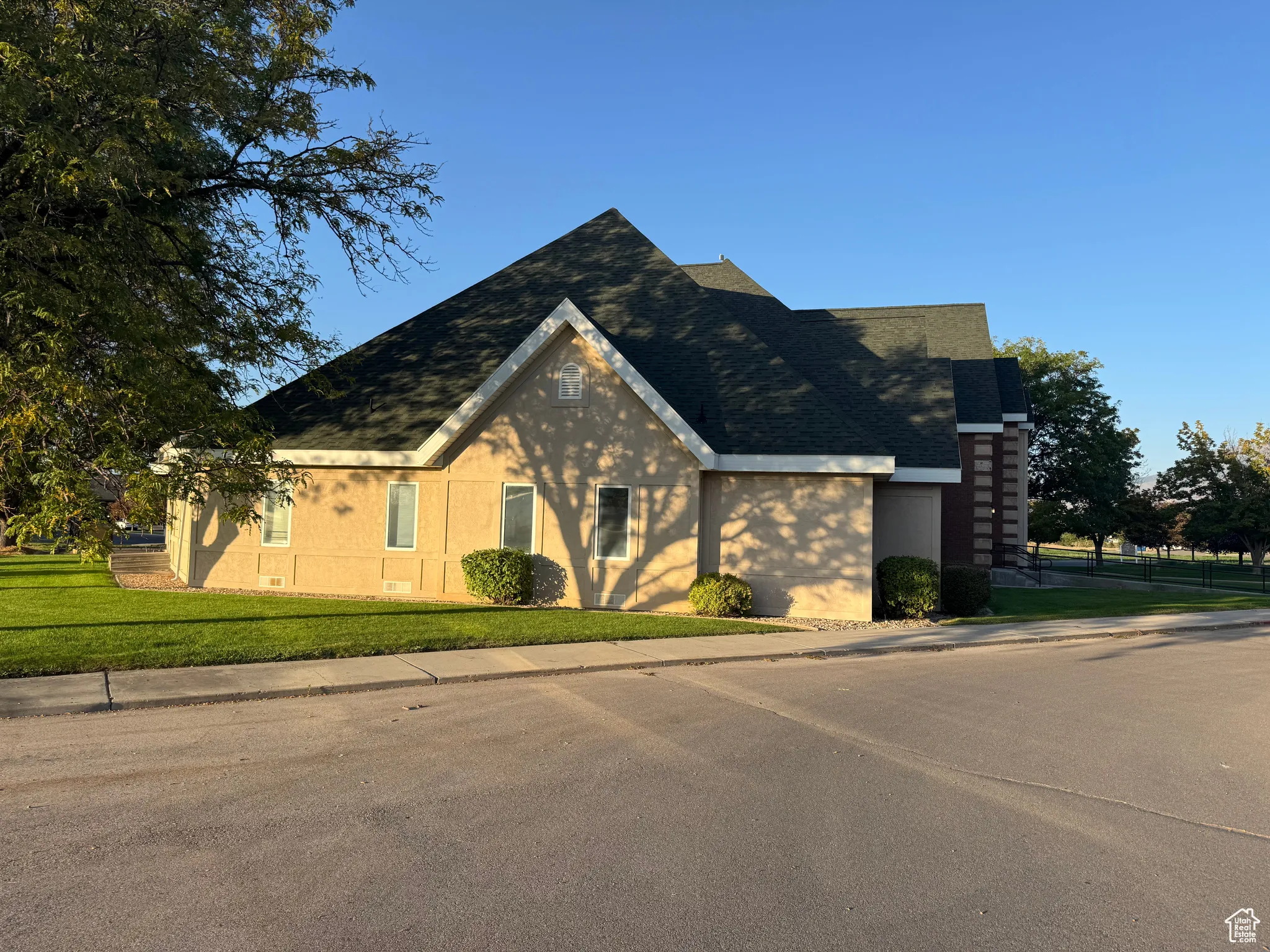View of exterior with roof with shingles, a yard, and brick siding