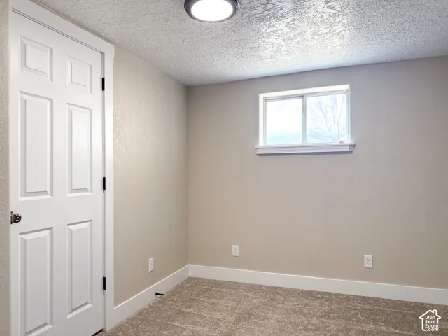 Carpeted empty room featuring baseboards and a textured ceiling