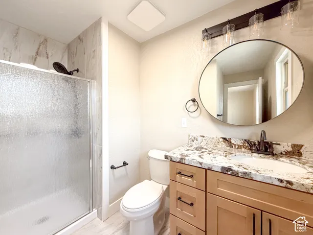 Bathroom featuring a shower stall, vanity, and a textured wall