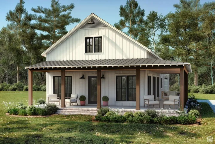 Rear view of house with board and batten siding, a yard, and covered porch