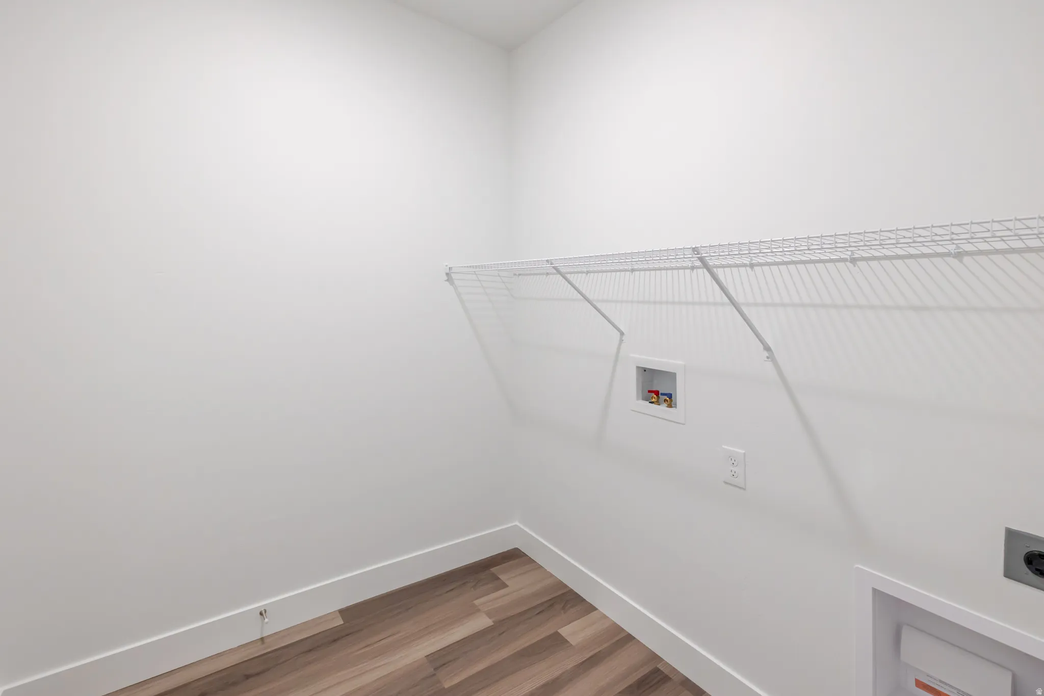 Laundry room with light wood finished floors, hookup for a washing machine, and hookup for an electric dryer