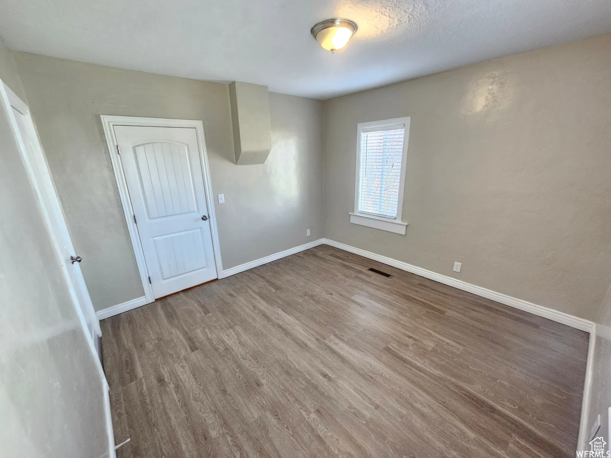 Unfurnished room with wood finished floors and a textured ceiling