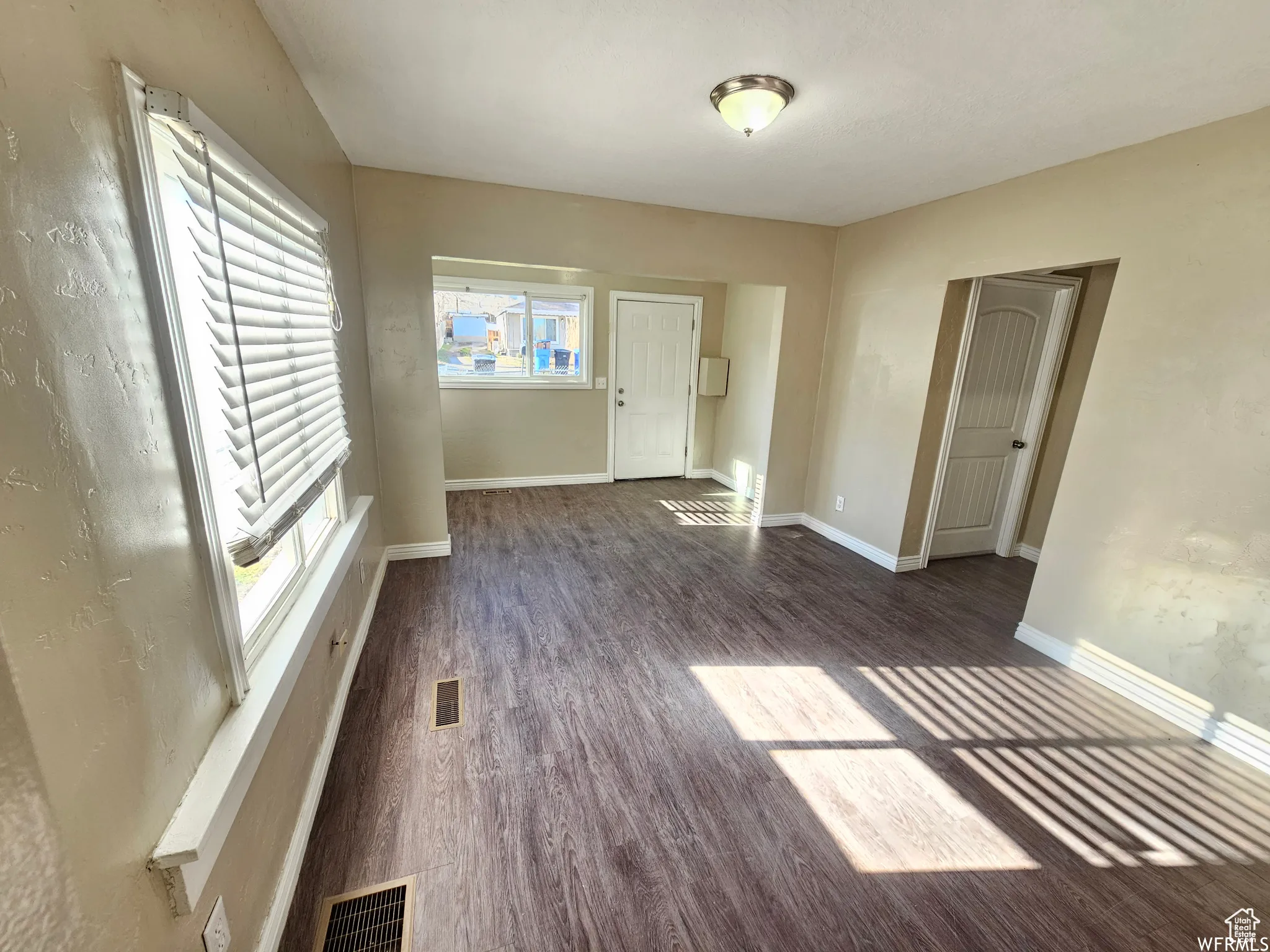 Unfurnished living room with baseboards and dark wood-style flooring