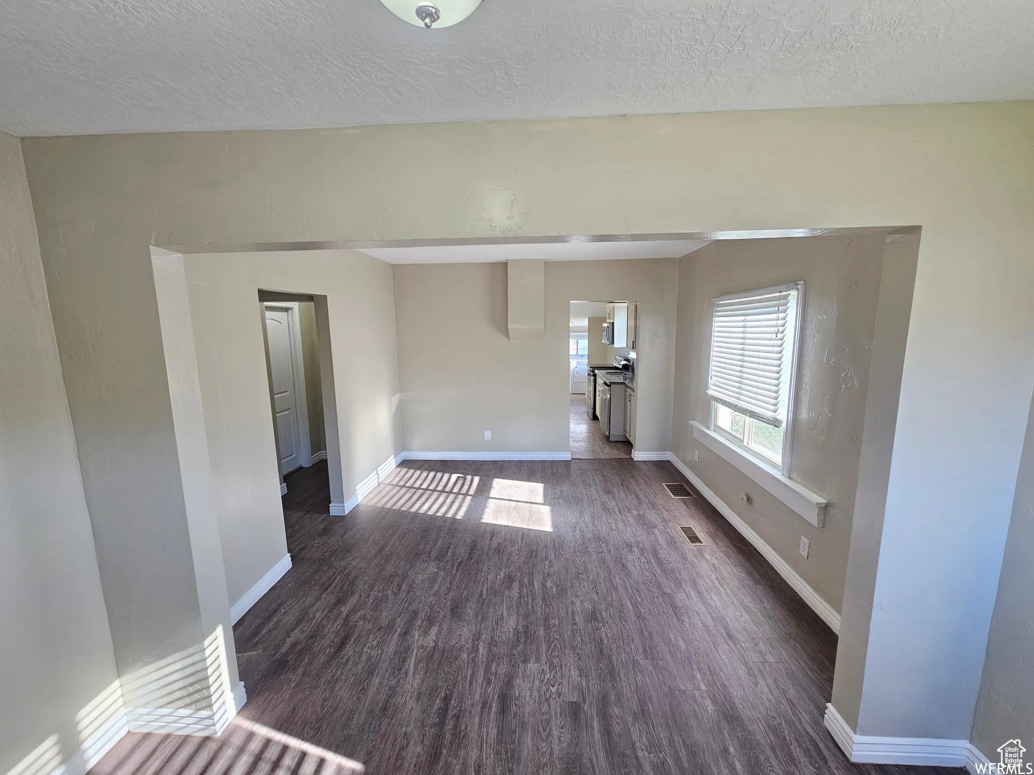 Unfurnished room featuring a textured ceiling and dark wood-style floors