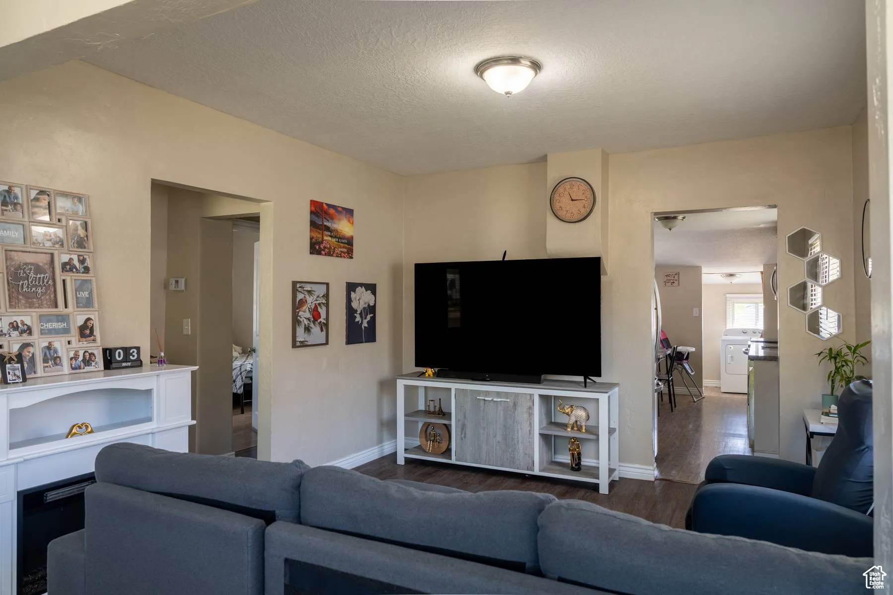 Living area featuring a textured ceiling, wood finished floors, and washer / dryer