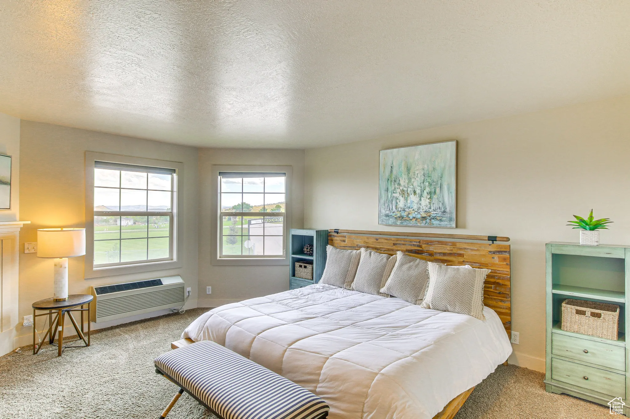 Carpeted bedroom with a textured ceiling and an AC wall unit