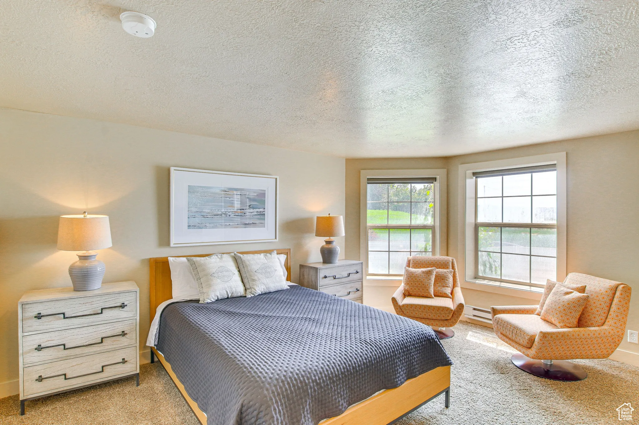 Bedroom with a textured ceiling, carpet flooring, and a baseboard heating unit