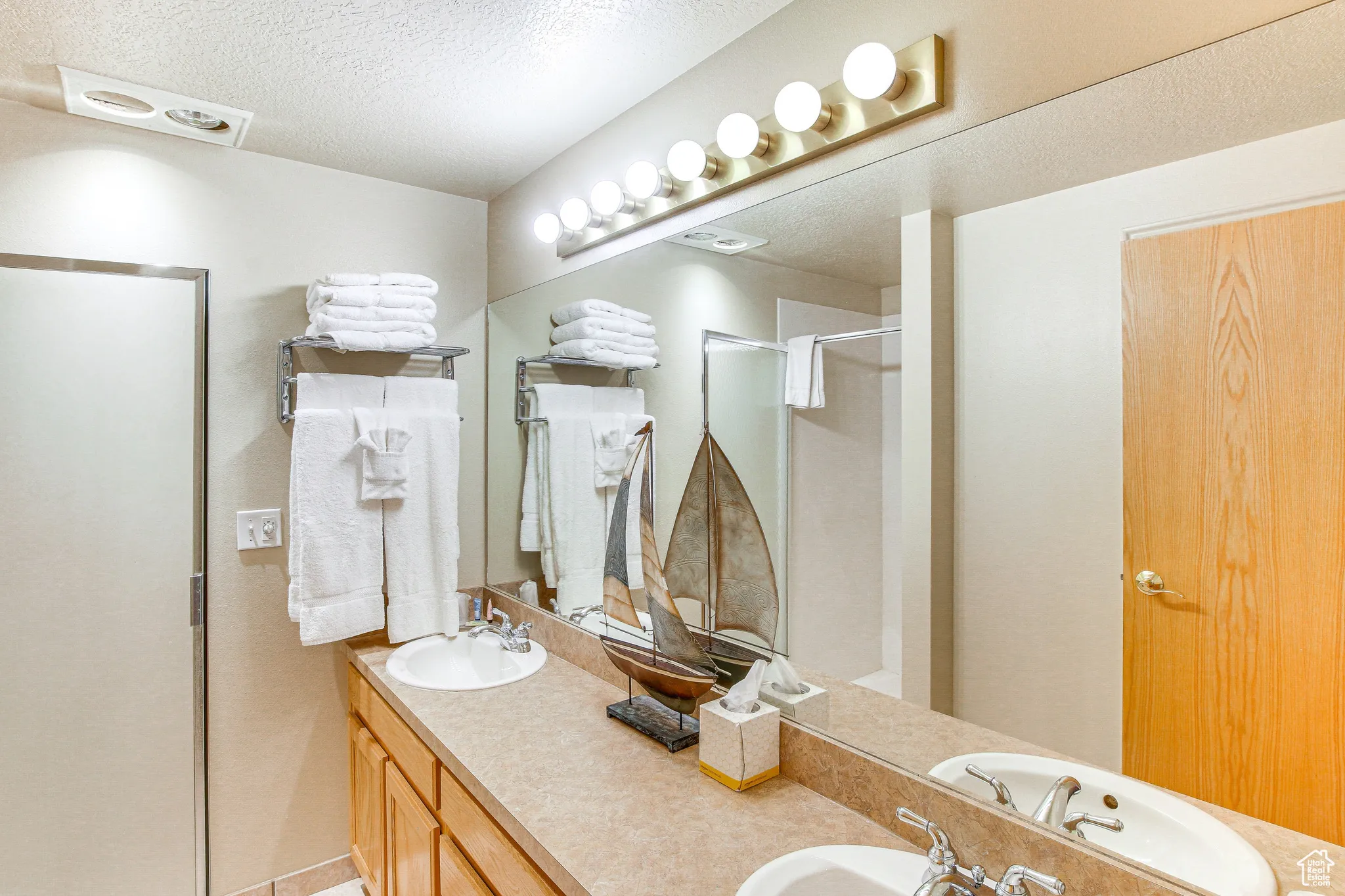 Bathroom with a textured ceiling, a stall shower, and double vanity