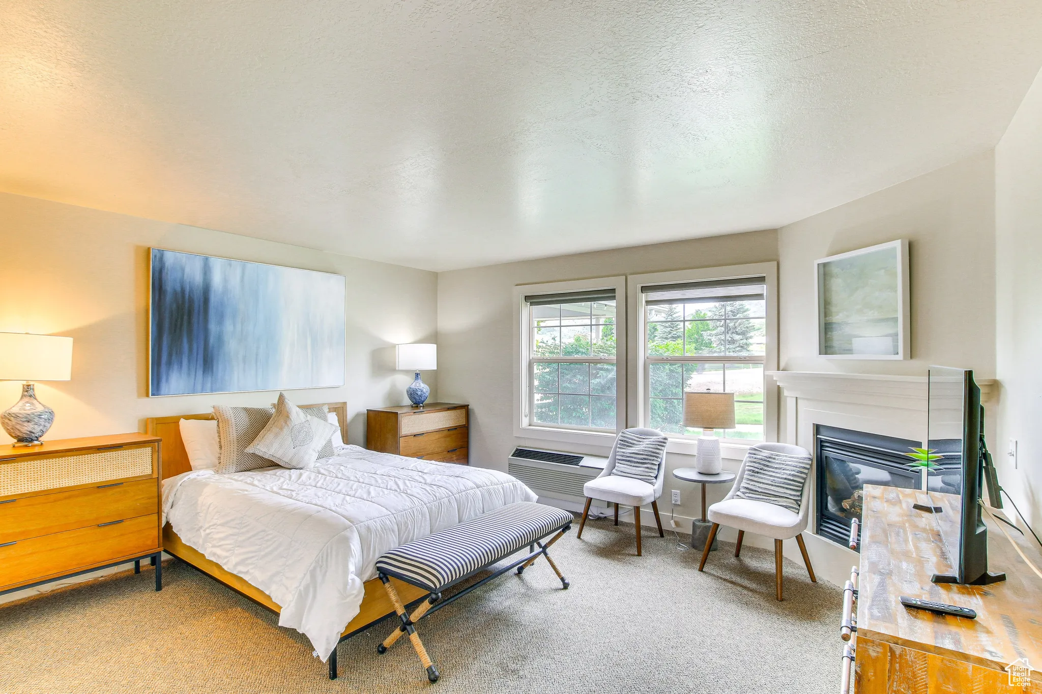 Carpeted bedroom with a textured ceiling and a glass covered fireplace