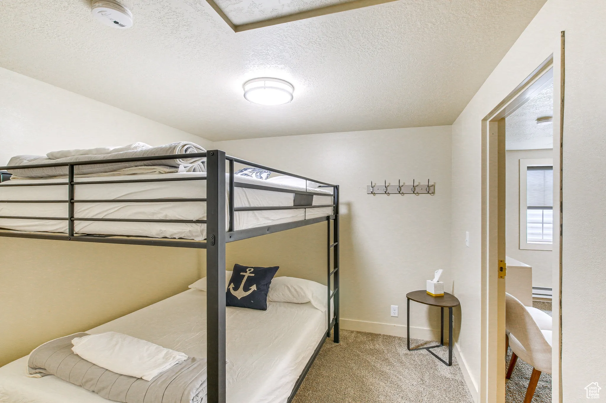 Bedroom with light colored carpet and a textured ceiling
