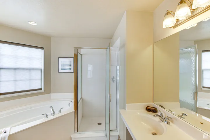 Bathroom featuring healthy amount of natural light, vanity, a bath, and a shower stall