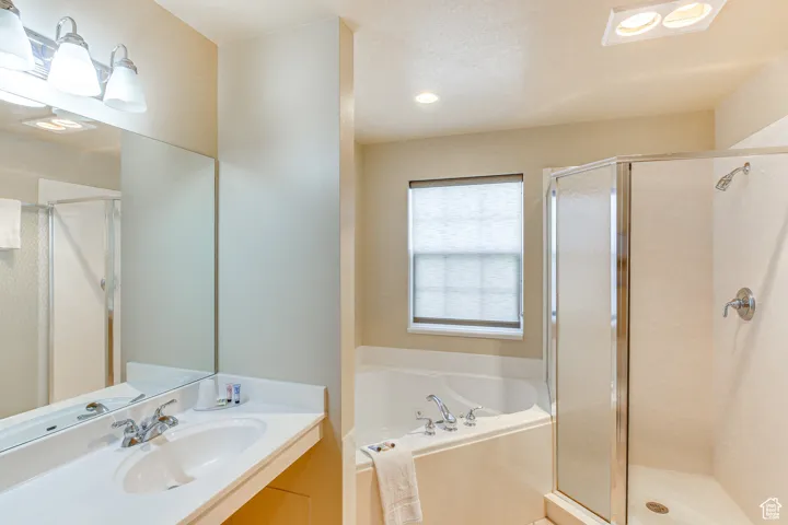 Full bathroom with vanity, a shower stall, a bath, and recessed lighting