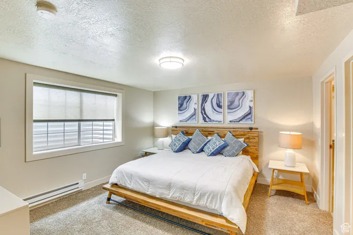 Bedroom featuring carpet flooring, a textured ceiling, and baseboard heating