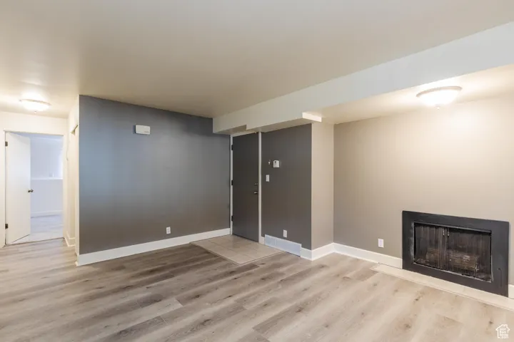 Unfurnished living room featuring light wood-style flooring and a fireplace with flush hearth