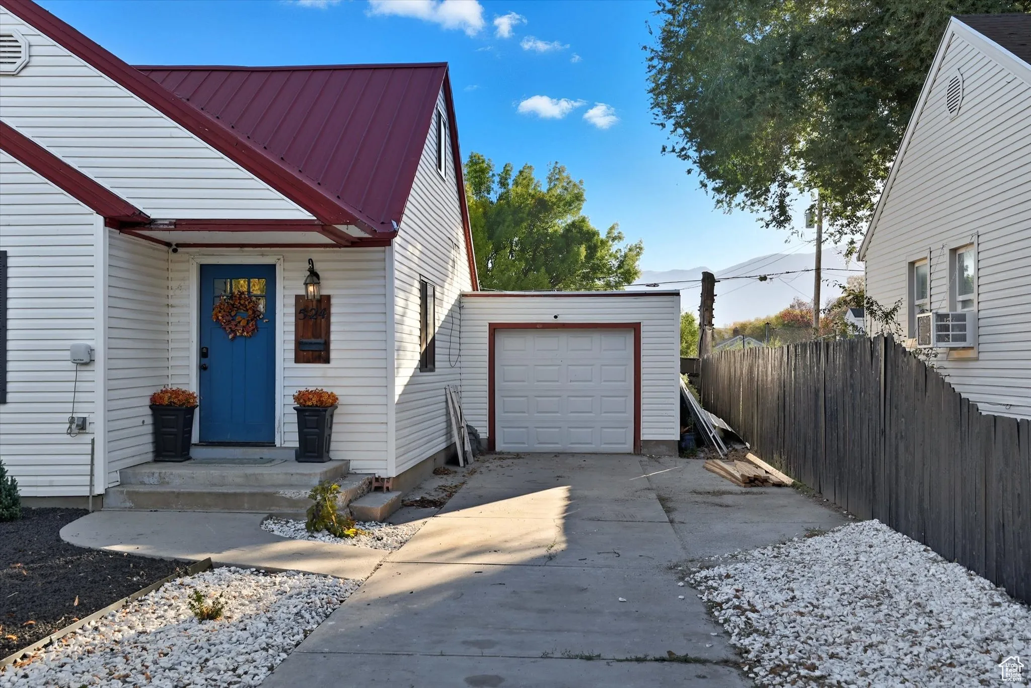 View of front of property featuring concrete driveway, a metal roof, and a garage