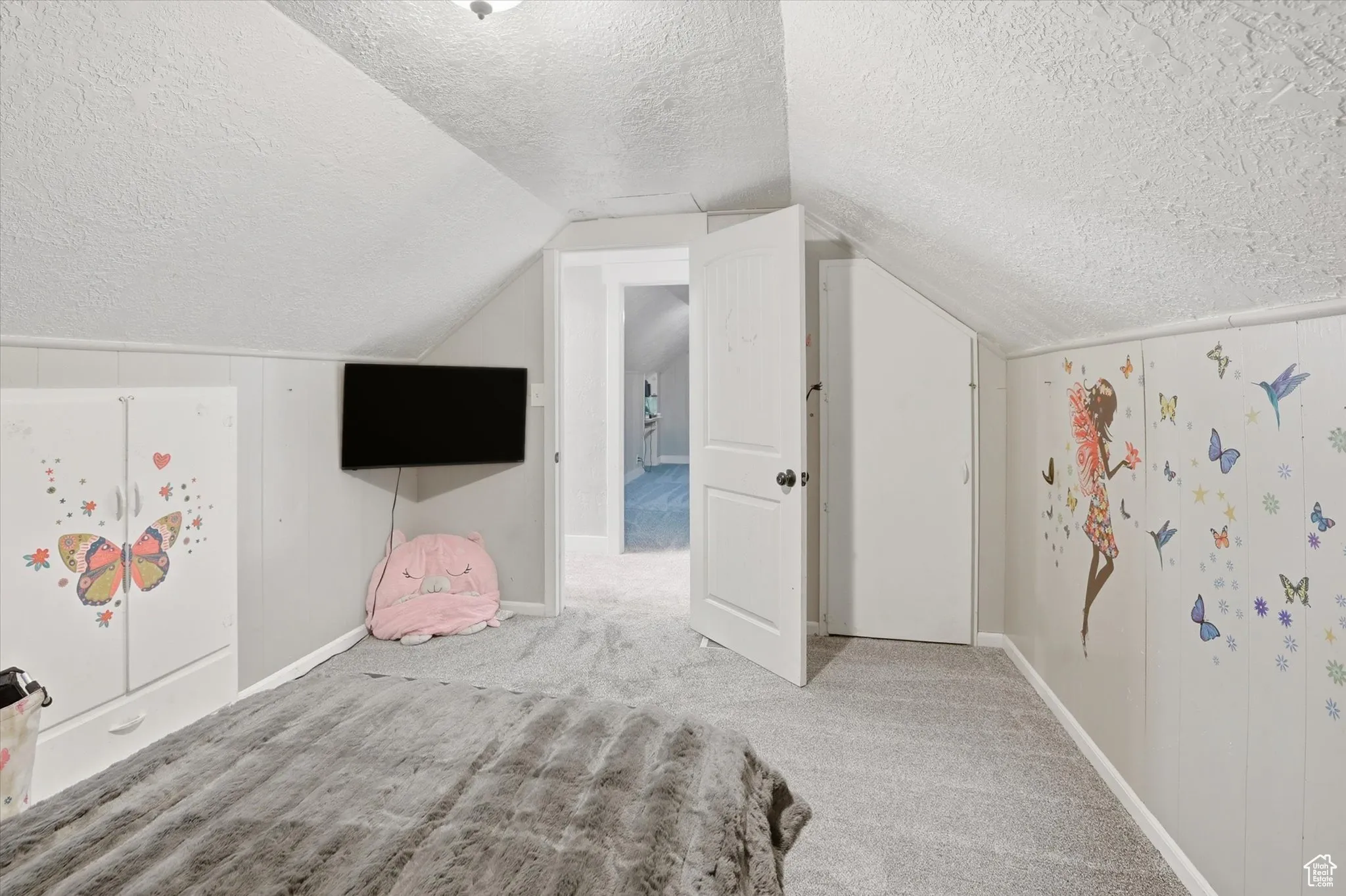 Unfurnished bedroom with carpet, a textured ceiling, and lofted ceiling