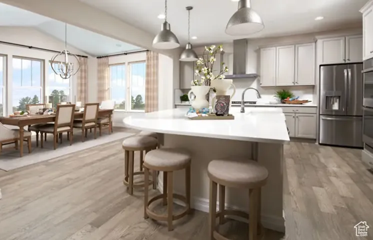 Kitchen with stainless steel appliances, decorative light fixtures, a breakfast bar area, light wood-type flooring, and a chandelier